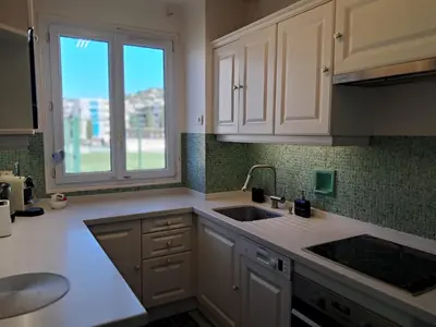 a kitchen with white cabinets and a sink and a window at LES MOUETTES A in Cannes