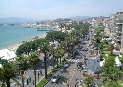 a busy city street with palm trees and the ocean at LES MOUETTES A in Cannes