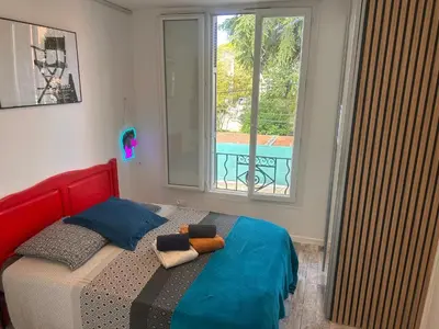 a bedroom with a bed with a red headboard and a window at Studio and gallery in Cannes
