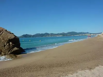 a beach with people swimming in the water at ToiTmer in Cannes