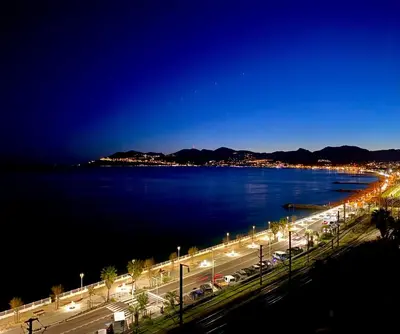 a night view of a city and a body of water at ToiTmer in Cannes