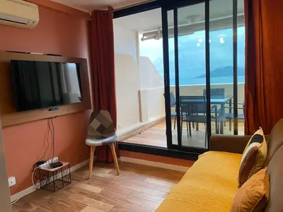 a living room with a television and a balcony with a table at ToiTmer in Cannes
