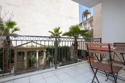 a balcony with a fence and a bench and palm trees at Palazzio Vieux Port by Welcome to Cannes in Cannes