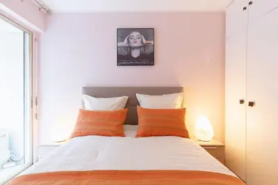 a bedroom with a bed with orange and white pillows at Magnifique 2 pièces Palm Beach bord mer in Cannes