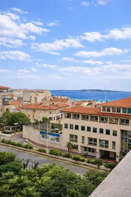 a city street with buildings and the ocean in the background at La vue d'Azur, élégance et lumière à Cannes in Cannes