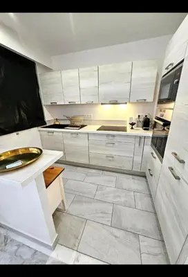 a kitchen with white cabinets and a tile floor at La vue d'Azur, élégance et lumière à Cannes in Cannes