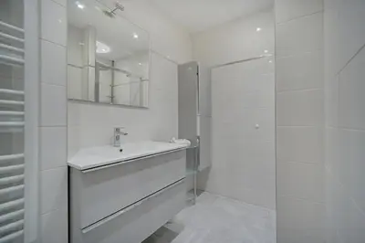 a white bathroom with a sink and a mirror at IMMOGROOM - Panoramic View - quiet - AC - bright in Cannes