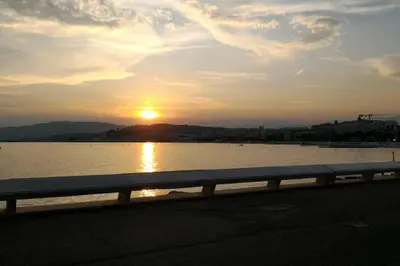 a sunset over a body of water with a fence at CANNES in Cannes