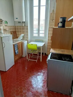 a kitchen with a stove and a table with a green chair at CANNES in Cannes