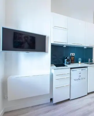 a kitchen with white cabinets and a tv on the wall at Studio Léa in Cannes