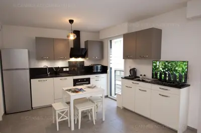 a kitchen with white cabinets and a table with chairs at Carre Ginger in Cannes