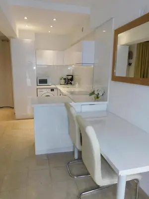 a white kitchen with a white table and chairs at Lovely 1 Bedroom Boulevard de la Croisette in Cannes