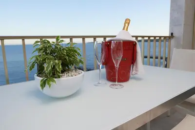 a table with two glasses and a plant on a balcony at Palm Beach Amazing view in Cannes