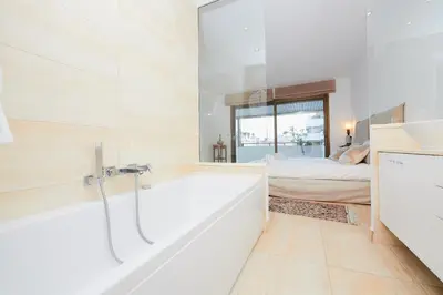 a white bathroom with a tub and a bedroom at Appartement privé vue mer Cannes centre Gray d'Albion in Cannes