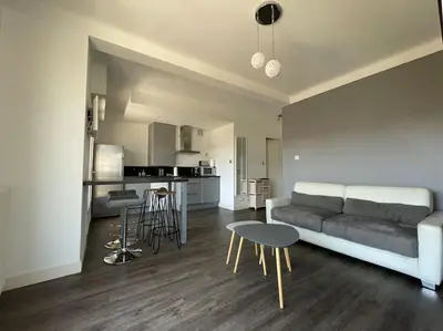 a living room with a couch and a table and a kitchen at Le Maria - Cannes - Renovated Feb 2025 in Cannes