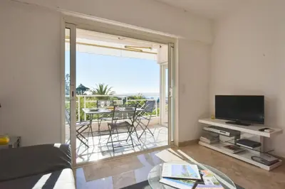 a living room with a television and a table with chairs at 1-Br Sea view Luxury Residential with pool in Cannes