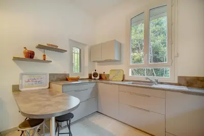 a kitchen with white cabinets and a wooden table at IMMOGROOM - Villa in the city center with terrace- garden in Cannes