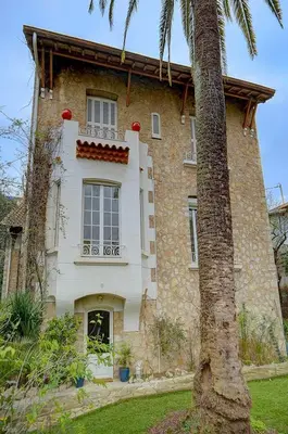 a building with a palm tree in front of it at IMMOGROOM - Villa in the city center with terrace- garden in Cannes