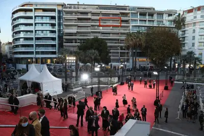 a group of people walking on a red floor in front of a building at Cannes - Croisette - Palais des Festivals in Cannes