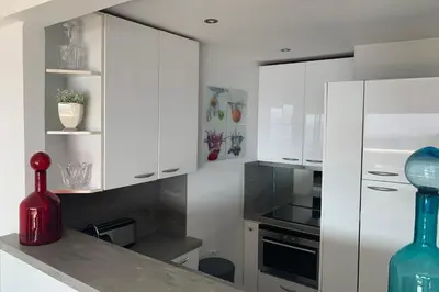 a kitchen with white cabinets and a red vase on a counter at Cannes - Croisette - Palais des Festivals in Cannes