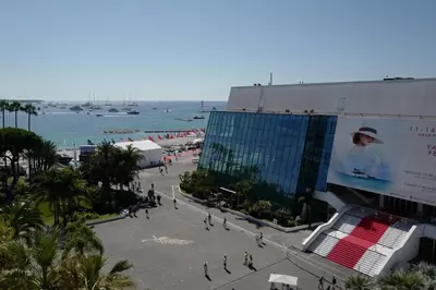a crowd of people walking on a sidewalk near the water at Cannes - Croisette - Palais des Festivals in Cannes