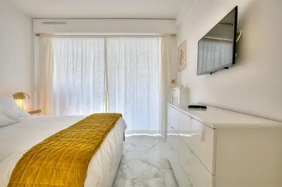 a bedroom with a bed with a television on a wall at Luxury 4 Stars Apartment with 2 Terraces, Cannes Croisette in Cannes