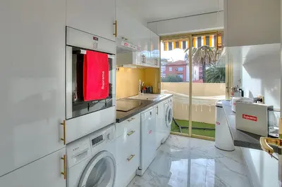 a white kitchen with a sink and washing machines at Luxury 4 Stars Apartment with 2 Terraces, Cannes Croisette in Cannes