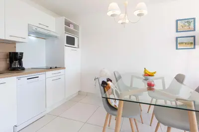 a white kitchen with a glass table and chairs at Villa Francia in Cannes