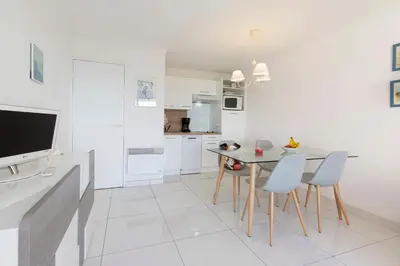 a white kitchen with a dining table and chairs at Villa Francia in Cannes