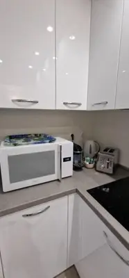 a kitchen with white cabinets and a white microwave at Le Castille - à deux pas des plages in Cannes