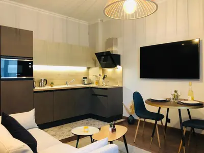 a living room with a couch and a kitchen at I Cannes Sleep - Centre ville au calme in Cannes