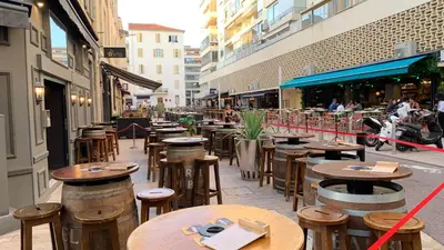 a row of wooden tables and stools on a city street at Village Croisette in Cannes