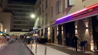 a street with people sitting outside of a building at night at Village Croisette in Cannes