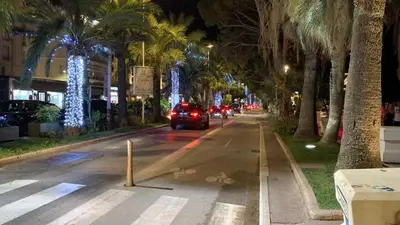 a car driving down a street with palm trees at night at Village Croisette in Cannes