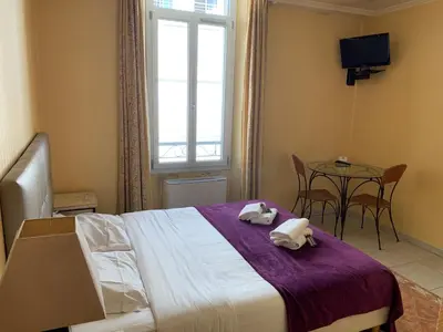 a bedroom with a bed and a table and a window at Village Croisette in Cannes