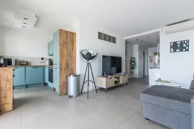 a kitchen and a living room with blue cabinets at LB Vacation Rentals I Admire Panoramic Ocean Views Through Walls of Windows in Cannes