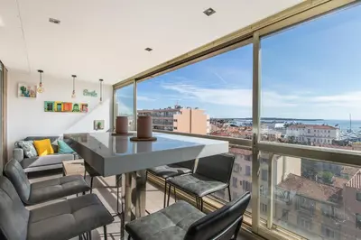 a room with a table and chairs and a large window at LB Vacation Rentals I Admire Panoramic Ocean Views Through Walls of Windows in Cannes