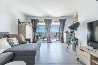 a living room with a couch and a television at LB Vacation Rentals I Admire Panoramic Ocean Views Through Walls of Windows in Cannes