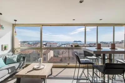 a living room with a table and chairs and a large window at LB Vacation Rentals I Admire Panoramic Ocean Views Through Walls of Windows in Cannes