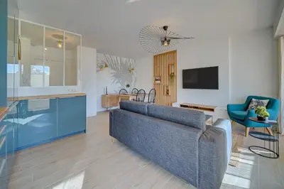a living room with a blue couch and a tv at IMMOGROOM- Renovated- Large terrace- AC- Shops- Parking in Cannes