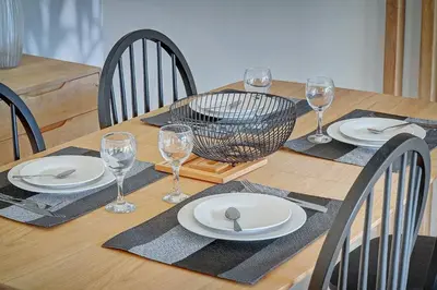 a wooden table with plates and wine glasses on it at IMMOGROOM- Renovated- Large terrace- AC- Shops- Parking in Cannes