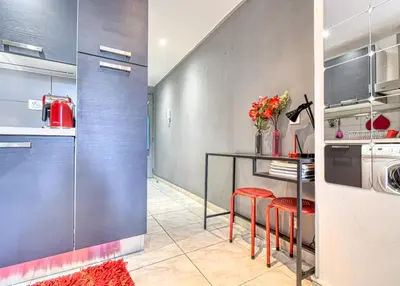 a kitchen with a counter and a table with red stools at Beautiful modern apartment in the heart of Cannes in Cannes
