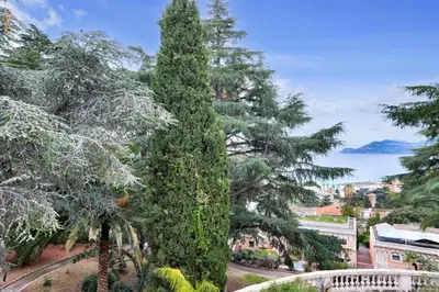 a tall green tree in a city with a lake at Résidence Cannes Villa Francia - maeva Home - Appartement climatisé 3 pièces 4 personnes - Prestige - super Home MAE-6737 in Cannes