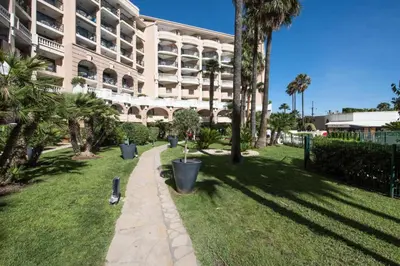 a large building with palm trees and a sidewalk at Résidence Cannes Verrerie - maeva Home - Appartement 3 Pièces 6 Personnes - Sélection MAE-4213 in Cannes