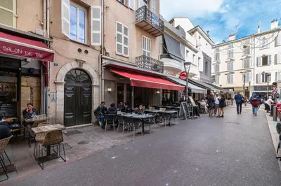a street with tables and chairs and people walking down the street at Beautiful and cozy apartment in the heart of Cannes in Cannes