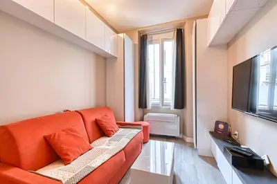 a living room with an orange couch and a television at Beautiful and cozy apartment in the heart of Cannes in Cannes