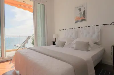 a white bedroom with a large bed and a large window at Charming Apartment on Seafront with Rooftop in Cannes