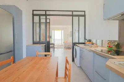 a kitchen with a wooden table and a dining room at Charming Apartment on Seafront with Rooftop in Cannes