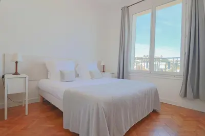 a white bed in a room with a large window at Charming Apartment on Seafront with Rooftop in Cannes