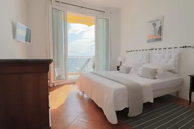 a bedroom with a large white bed and a large window at Charming Apartment on Seafront with Rooftop in Cannes